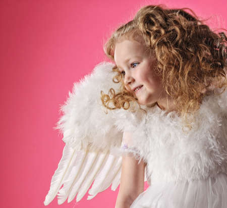 Beautiful little angel girl isolated on pink backgroundの写真素材