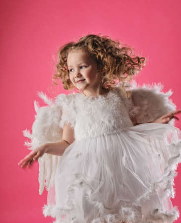 Beautiful little angel girl isolated on pink backgroundの写真素材