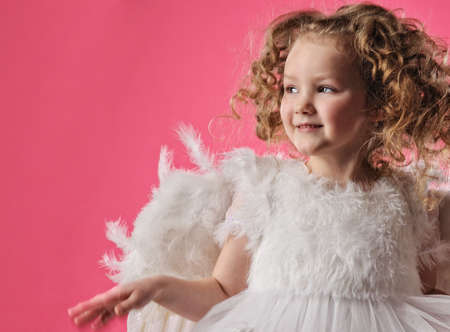 Beautiful little angel girl isolated on pink backgroundの写真素材