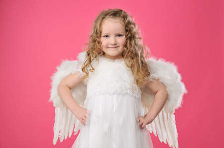 Beautiful little angel girl isolated on pink backgroundの写真素材