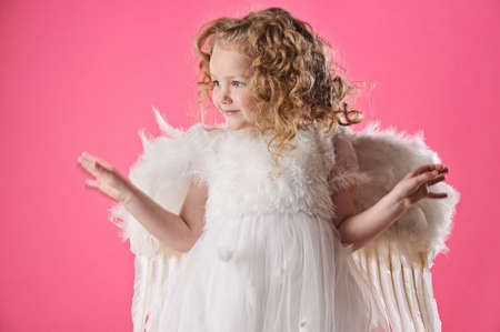 Beautiful little angel girl isolated on pink background