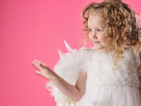 Beautiful little angel girl isolated on pink backgroundの写真素材