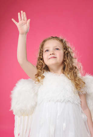 Beautiful little angel girl isolated on pink backgroundの写真素材