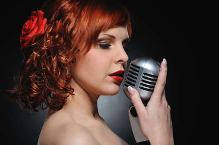 Attractive redhead woman with retro microphoneの写真素材