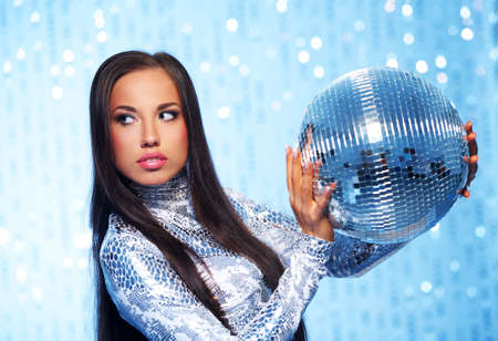 Brunette woman with a disco ball over abstract backgroundの写真素材