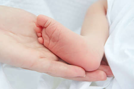Mothers hand holding her newborn baby feetの写真素材