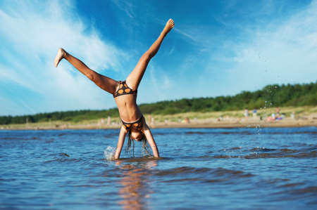 young girl making cartwheel in the waterの写真素材