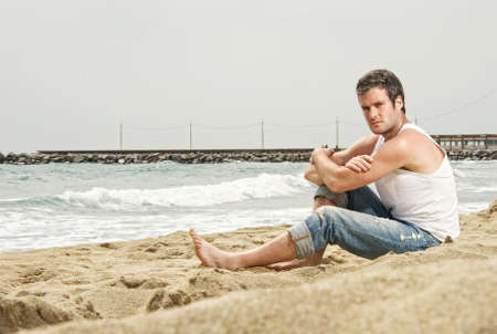 Handsome man sitting on a beachの写真素材