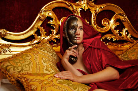 Beautiful woman with a carnival mask lying on bed