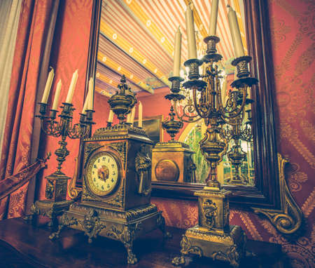 Antique clock and chandelier against mirrorの写真素材
