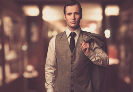 Man in waistcoat with jacket over his shoulder against blurred backgroundの写真素材