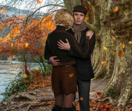 Elegant couple embracing near river in autumnal landscape
