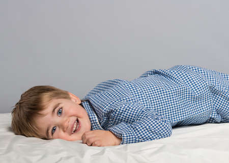 Little boy wearing blue pyjamas in bedの写真素材