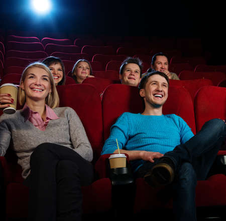 Group of smiling people watching movie in cinema