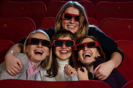 Group of excited young girls watching movie in cinemaの写真素材