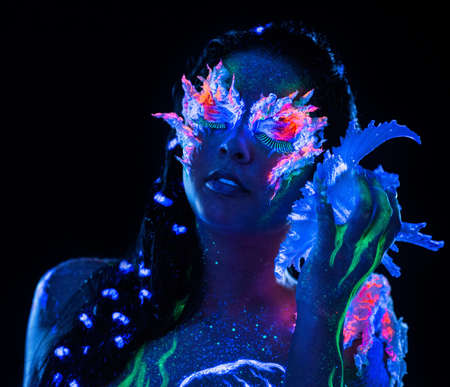 Portrait of beautiful woman with body art glowing in ultraviolet lightの写真素材