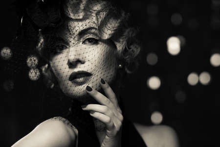 Monochrome picture of 
elegant blond retro woman   wearing little hat with veil 
