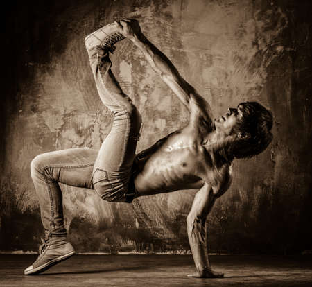 Toned picture of young man with torso doing acrobatic movements 