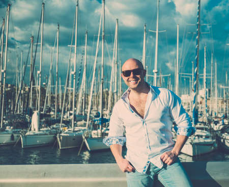 Happy middle-aged man in shirt against yacht portの写真素材