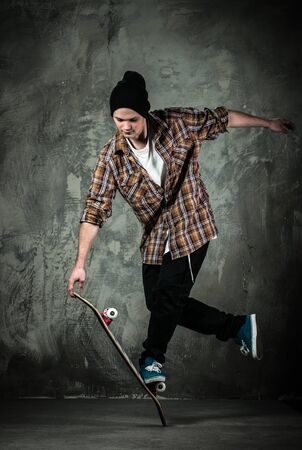 Young man in hat and shirt performing stunt on skateboardの写真素材