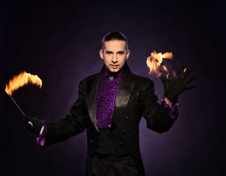Young brunette magician in stage costume performing flame tricks の写真素材