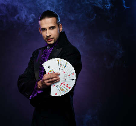 Young brunette magician in stage costume showing card tricks 