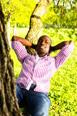 Young smiling african american lying on a tree branch in a park  の写真素材