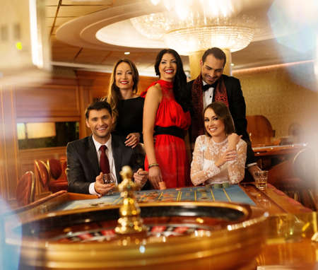 Group of young people behind roulette table in a casinoの写真素材