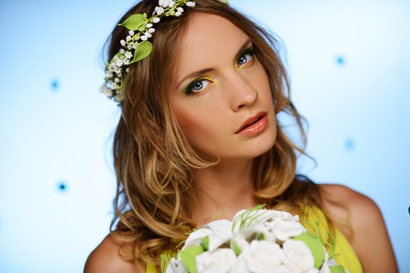 Girl in yellow dress with may-lily chaplet and bouquet on blue background の写真素材
