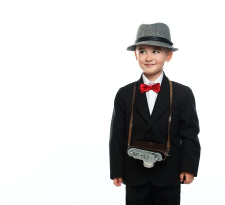 Little boy in hat and black suit with vintage camera isolated on white background の写真素材