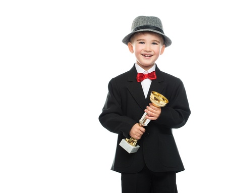 Happy boy in black suit holding prize cupの写真素材