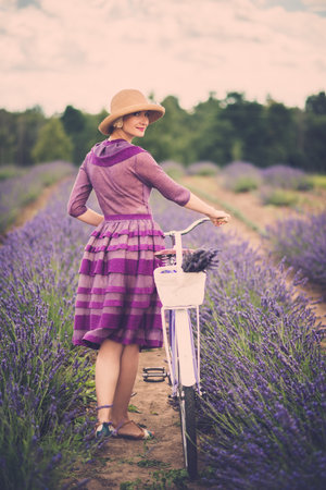 Woman in purple dress and hat with retro bicycle in lavender fieldの写真素材