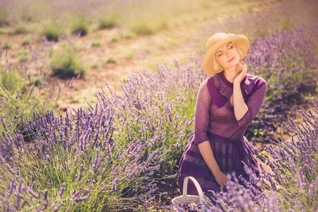 Woman in purple dress and hat with basket in lavender fieldの写真素材