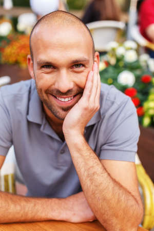 Positive middle-aged man alone behind table in summer cafeの写真素材