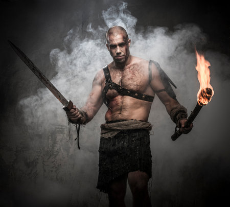 Gladiator standing in a smoke with torch and swordの写真素材