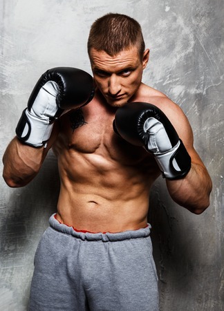 Young sporty man in boxing gloves posing の写真素材