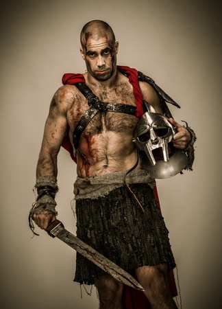 Wounded gladiator with sword covered in blood and helmet isolatedの写真素材