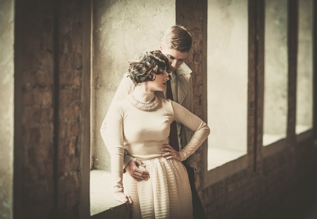 Beautiful vintage style couple standing near windowの写真素材