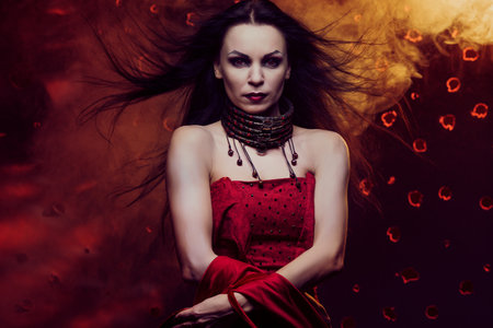 Beautiful vampire woman in red dress with waving hair