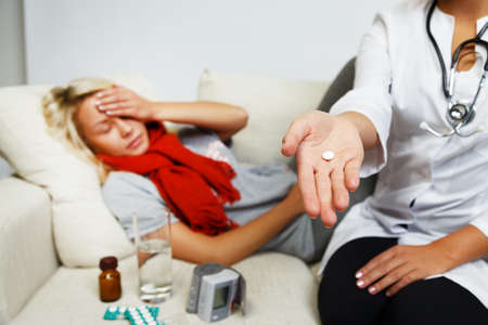 Female doctor giving pill to a sick young woman の写真素材