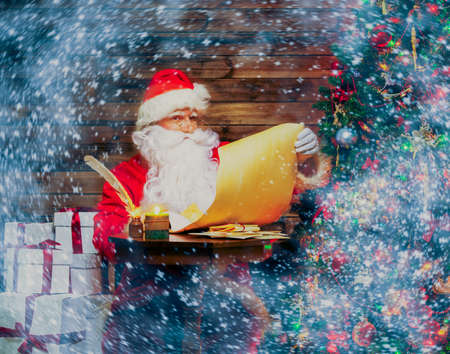 Santa Claus in wooden home interior reading wish list scrollの写真素材