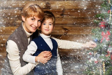 Happy mother and her lIttle boy decorating christmas tree in wooden house interior の写真素材