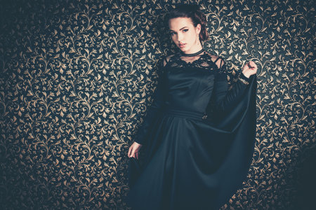 Beautiful young girl wearing black evening dress in luxury interior の写真素材