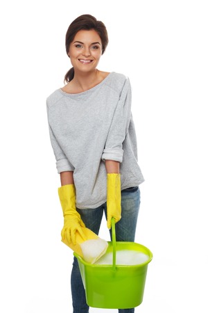 Beautiful cheerful brunette woman in gloves with sponge and bucketの写真素材