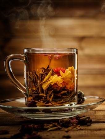 Glass cup with tea flower against wooden background の写真素材