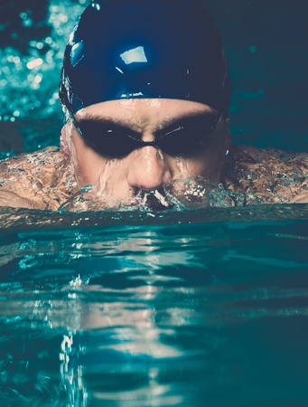 Muscular young man in blue cap in swimming poolの写真素材