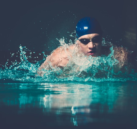 Muscular young man in blue cap in swimming poolの写真素材