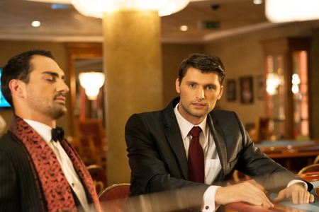 Two young well-dressed men behind gambling table in a casinoの写真素材