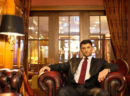 Confident handsome brunette sitting in luxury interior の写真素材