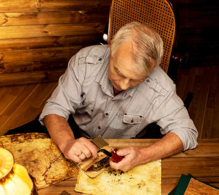 Senior man with smoking pipe in homely wooden interior の写真素材